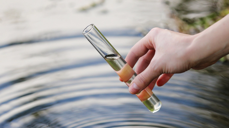 hand collects water sample ayer ma